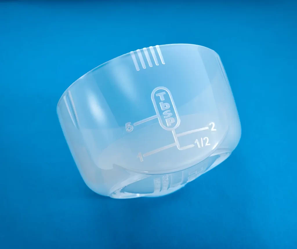 Translucent measuring cap that holds up to 1 cup of chemicals. TruDose Cap™ is on a blue background. Measurements are in tablespoons.